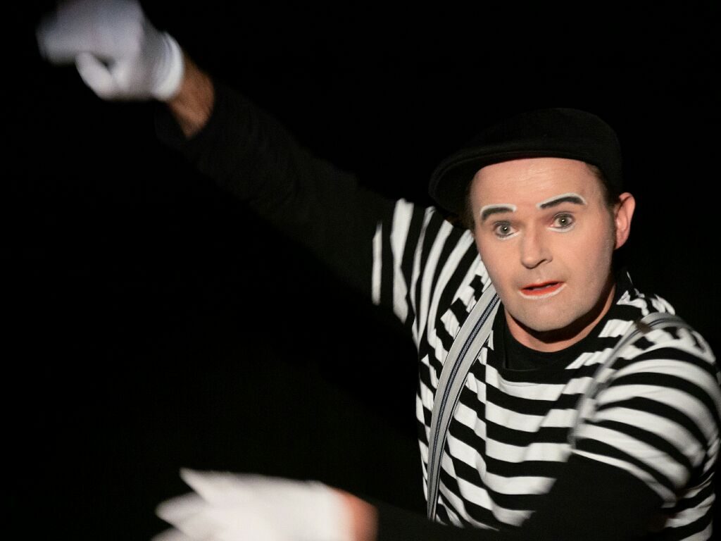 Pantomimekünstler in Schwarz-Weiß gestreiftem Outfit mit weißen Handschuhen.