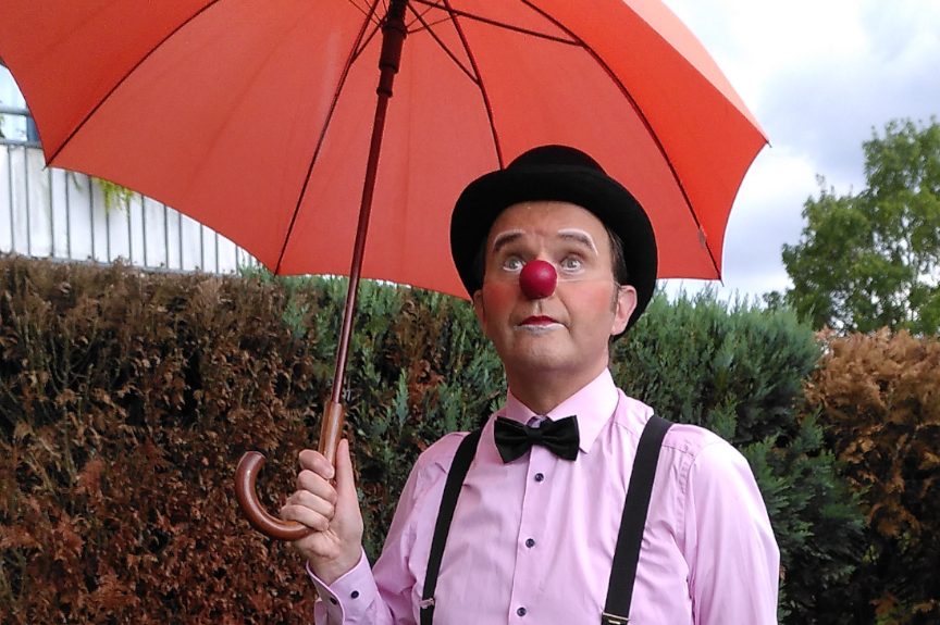 Clown mit roter Nase, Zylinder und Regenschirm